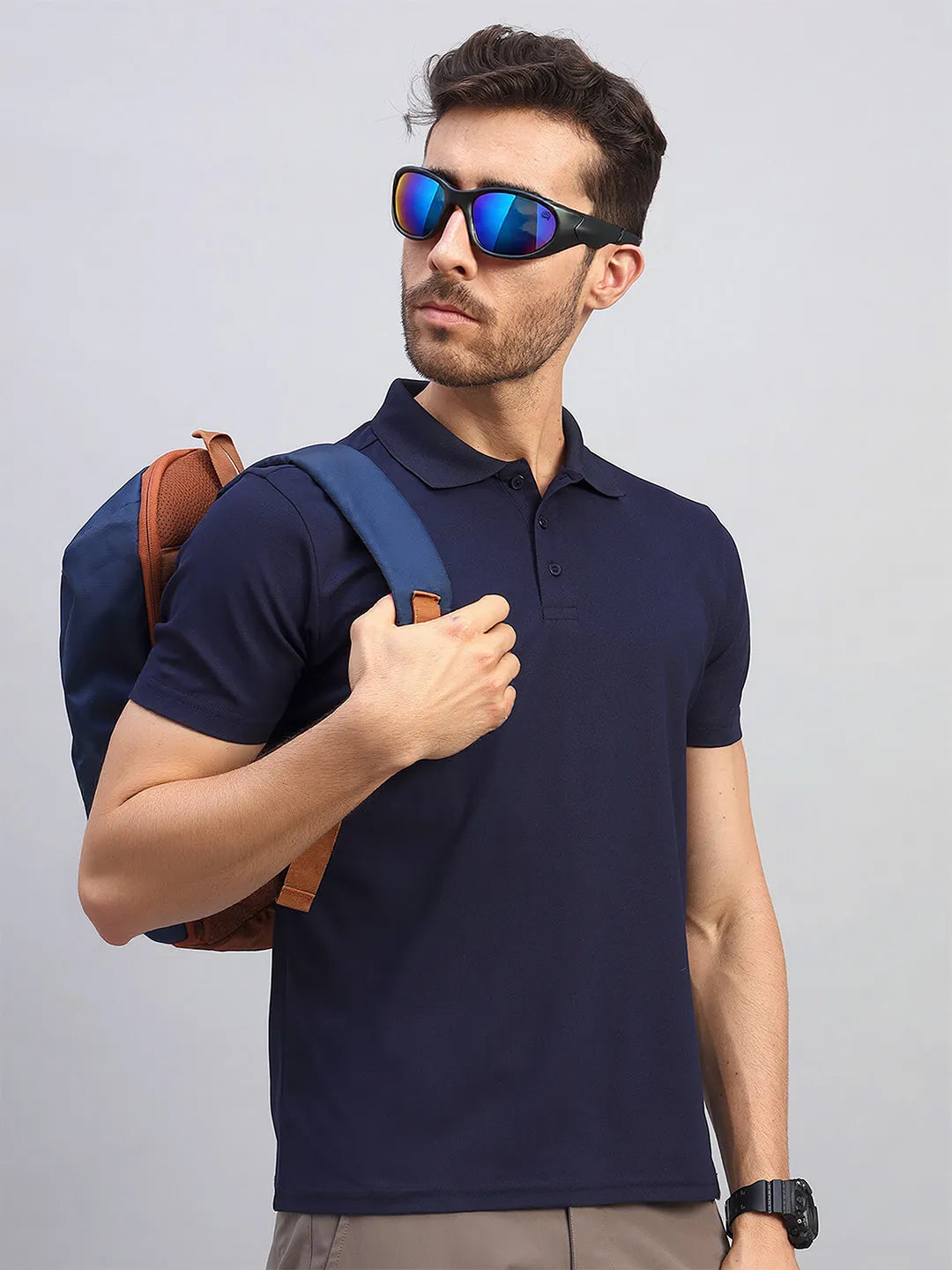 Man wearing the Reccy Men's Navy Blue Polo T-Shirt with a backpack, upper body view