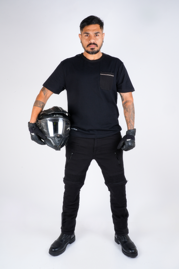 Rider in Genesis 2.0 Jet Black riding jeans, front view, holding a helmet